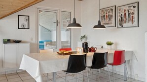 Eine moderne Küche mit Essbereich, ausgestattet mit Holzboden, weißen Wänden und einem großen Fenster.
