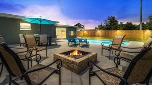 A backyard with a fire pit, outdoor seating, a pool, and a wooden fence. - Pool 5BR/3BA Launchpad (Titusville)
