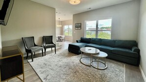 En stue med sofa, to lænestole, sofabord og fjernsyn.