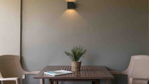 A small, square wooden table with a woven plant pot and a book on it, flanked by two wicker chairs. - CASA ARTE- Modern Apt+ Car option & Pool (Willemstad)