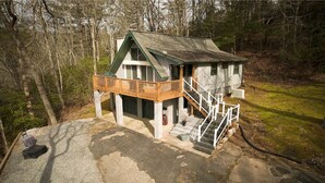 A cabin with a wooden deck, a staircase, and a concrete driveway. - Three-Bedroom Bungalow.... (Robbinsville)
