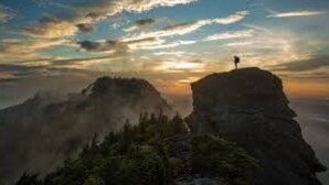 A person standing on a mountain peak with a view of the sky and clouds. - Three-Bedroom Bungalow.... (Robbinsville)