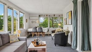 A modern living room with a sofa, a coffee table, and a dining area with chairs and a table.