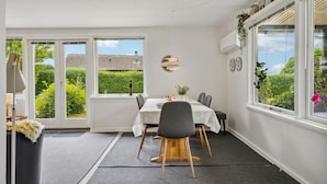 A dining area with a table set for four, a window with a view of greenery, and a ceiling with exposed beams.
