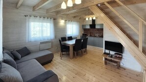 Una cabaña acogedora con interior de madera, comedor, sofá y chimenea.