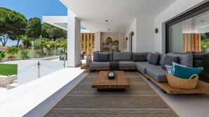 A modern living room with a large grey sectional sofa, a wooden coffee table, and a patterned rug. - All About Playas Andaluzas Villa (Marbella)