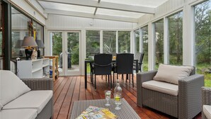 Une terrasse couverte, aménagée avec des meubles en osier, une table et des chaises.