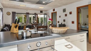 Une cuisine moderne dotée d’une cuisinière en acier inoxydable, de meubles blancs et d’une grande fenêtre offrant une vue sur l’extérieur.