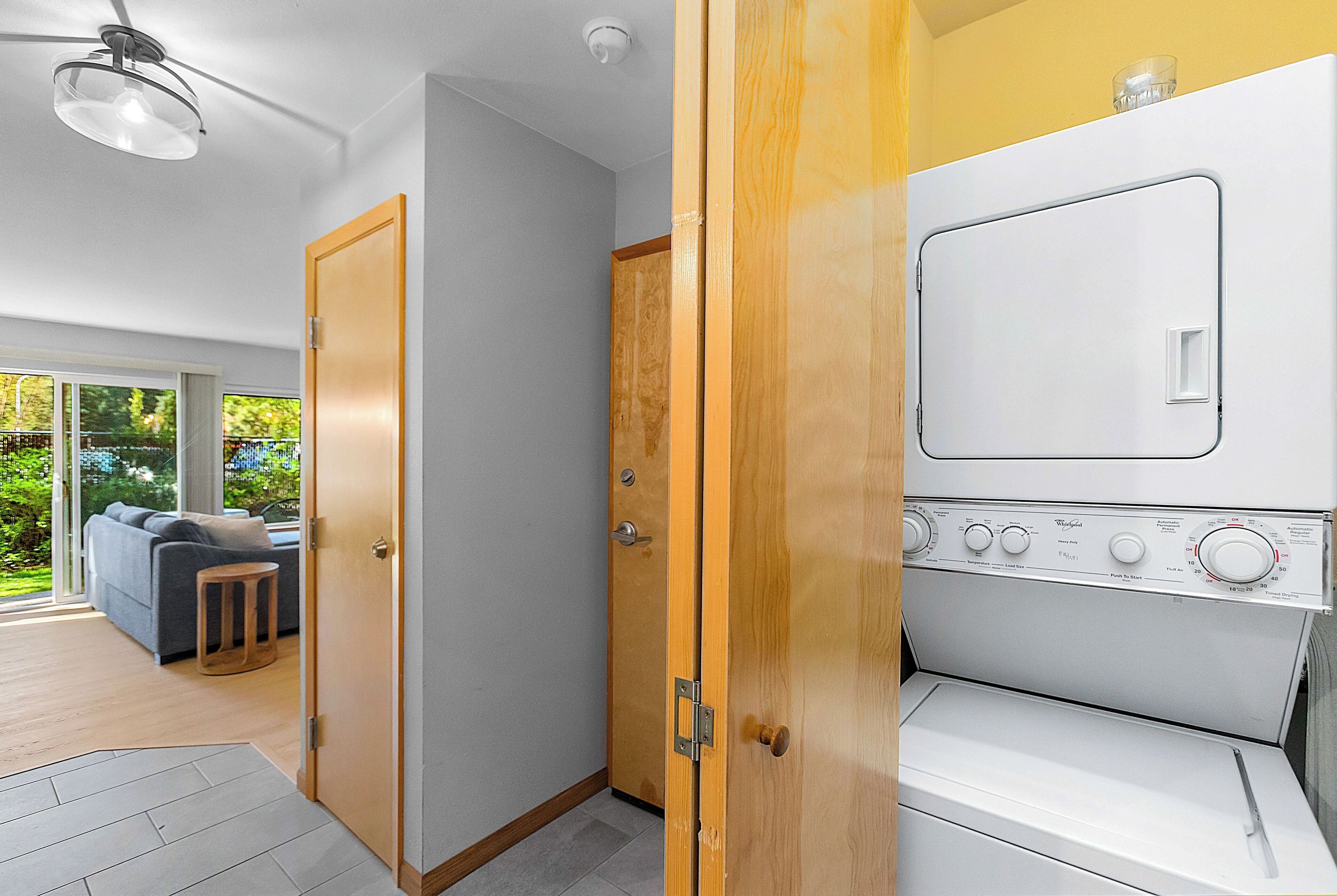 Eine moderne Küche mit Backofen und einer Holztür zu einem Wohnbereich mit Sofa und kleinem Tisch.