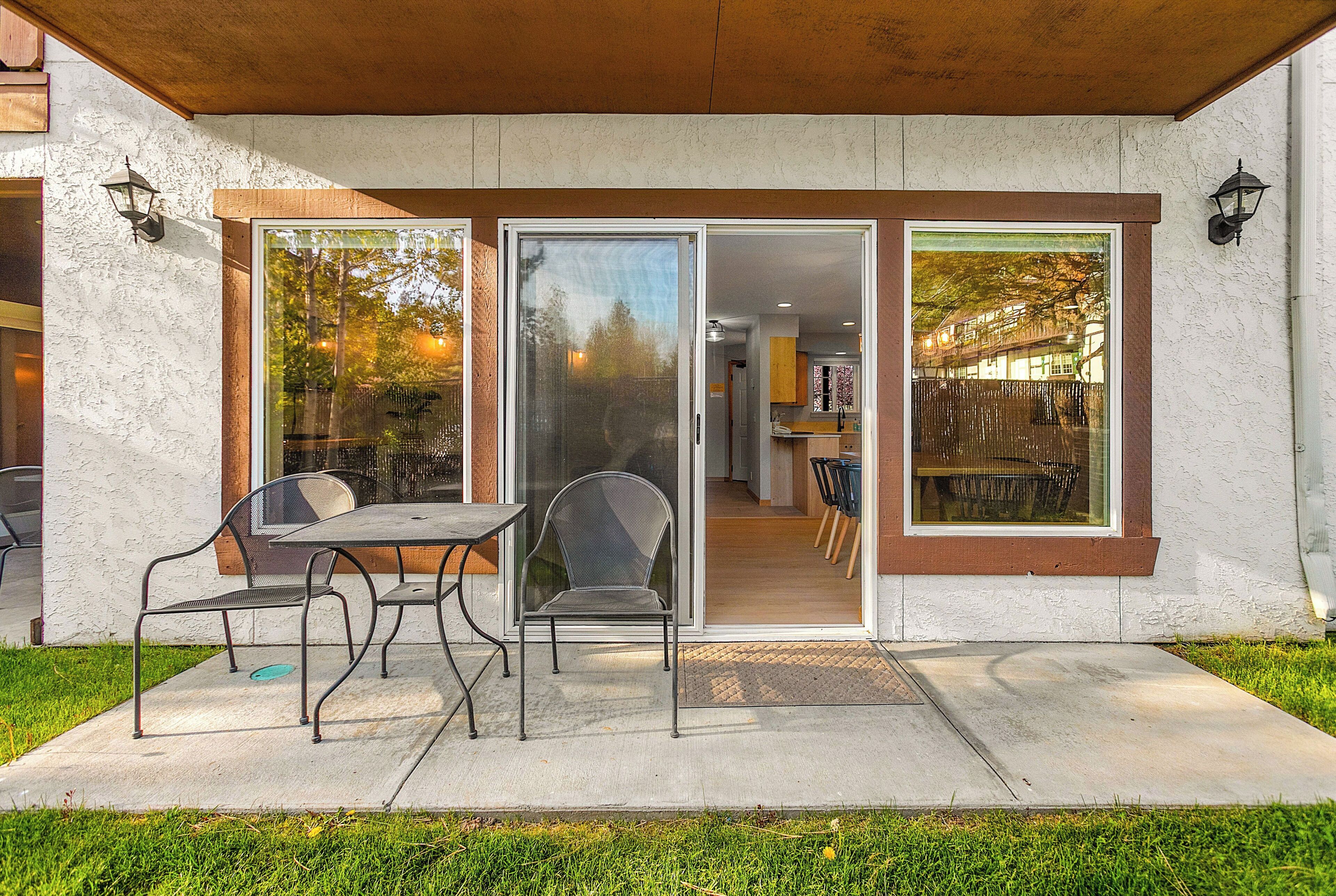 Une terrasse avec une table et des chaises, une porte-fenêtre coulissante et une vue sur l’intérieur.