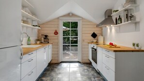 Cocina estrecha con armarios blancos, encimera de madera y vistas a una terraza exterior a través de una puerta de vidrio.