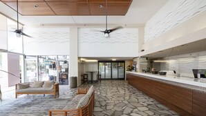 A spacious lobby with a reception desk, seating area, and a stone-patterned floor.