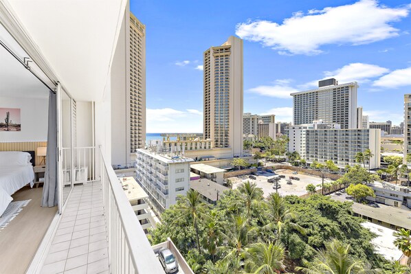 A high-rise hotel with multiple floors, balconies, and a view of the cityscape and palm trees.