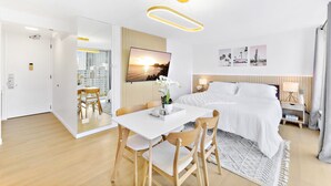 A modern hotel room with a bed, bedside table, lamp, and a large window.