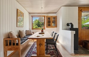 Un coin repas accueillant avec une table en bois, des bancs et une vue sur l’extérieur.