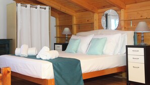 A wooden cabin-style bedroom with a bed, bedside lamps, a mirror, and a nightstand.
