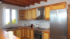 A kitchen with wooden cabinets, a stainless steel refrigerator, a microwave, and a stove.