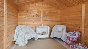 A cozy wooden cabin room with two single beds, a small white table, and a pink stroller. - Amazing home in Jægerspris with WiFi (Jægerspris)