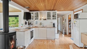 A modern kitchen with a wood stove, white cabinets, and a view of greenery outside. - Amazing home in Jægerspris with WiFi (Jægerspris)