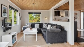 A modern living room with a wooden ceiling, a gray sofa, a white coffee table, and a TV mounted on the wall. - Amazing home in Jægerspris with WiFi (Jægerspris)