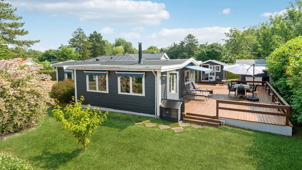 A modern house with a deck, a small attached garage, and a well-maintained lawn. - Amazing home in Jægerspris with WiFi (Jægerspris)