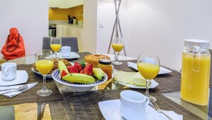 A breakfast table with fruits, juice, and a bottle of orange juice. - GuestReady - Exclusive Apartment at São Bento (Lisbon)