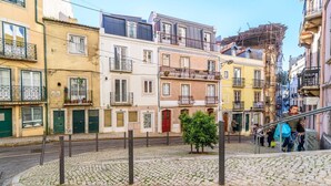 A cobblestone street with historic buildings, a small tree, and a staircase leading to an upper level. - GuestReady - Exclusive Apartment at São Bento (Lisbon)