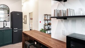 A modern kitchen with a black refrigerator, wooden table, and black cabinets. - Juno Lofts: Memories of Gastown (Stratford)