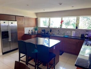 Enjoy meals in the kitchen with a central island, dining area, and large window offering a view of the surrounding greenery.