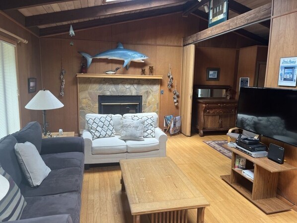 Cozy living room with a sofa set, flat-screen TV, and stone fireplace.