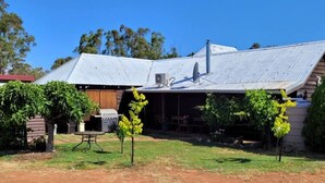 A rustic house with a corrugated metal roof, a wooden barn, and a small outdoor seating area with a table and chairs. - "Talbot" Rustic style accommodation with Mod Cons (Katrine)