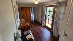 A room with a wooden floor, a dining table with chairs, a cabinet, and a door leading outside. - "Roseneath" Private room with en-suite, Rm 3 (Northam)