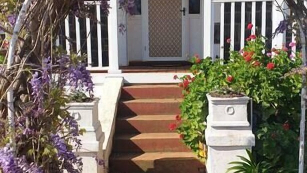 A pathway leading to a white door with a lattice design, surrounded by purple flowers and a small garden with red flowers. - "Roseneath" Private room with en-suite, Rm 3 (Northam)