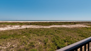 A coastal landscape with a clear sky, sandy beach, and grassy areas. - UPDATED Beach Front Condo - Holiday Isle 302 - Pool, Sauna, Hot Tub, Grill, W/D (Dauphin Island)