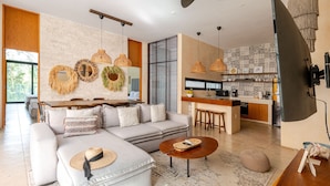 A modern living room with a sofa, coffee table, and decorative wall hangings. - Manor Tulum by The Spot Rentals (Tulum)