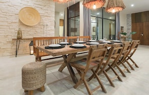A dining area with a wooden table set for six, surrounded by wooden chairs.