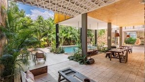 An outdoor patio area with seating, a pool, and lush greenery. - Manor Tulum by The Spot Rentals (Tulum)