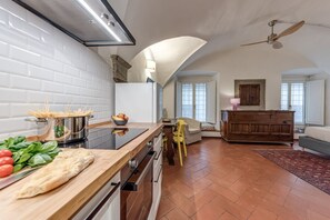 A kitchen with a wooden countertop, a stove, and a dining area with a chair and a table.