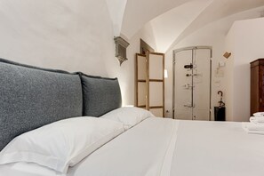 A bedroom with a large bed, a wardrobe, and a door leading to another room.