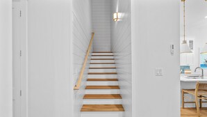 Una scala con gradini e corrimano in legno, che conduce a una stanza con una parete bianca e un lampadario.