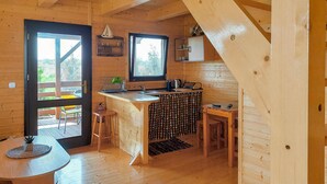A wooden cabin interior with a kitchen area, a dining table, and a bar. - 2 bedroom cozy home in Kladno (Kladno)