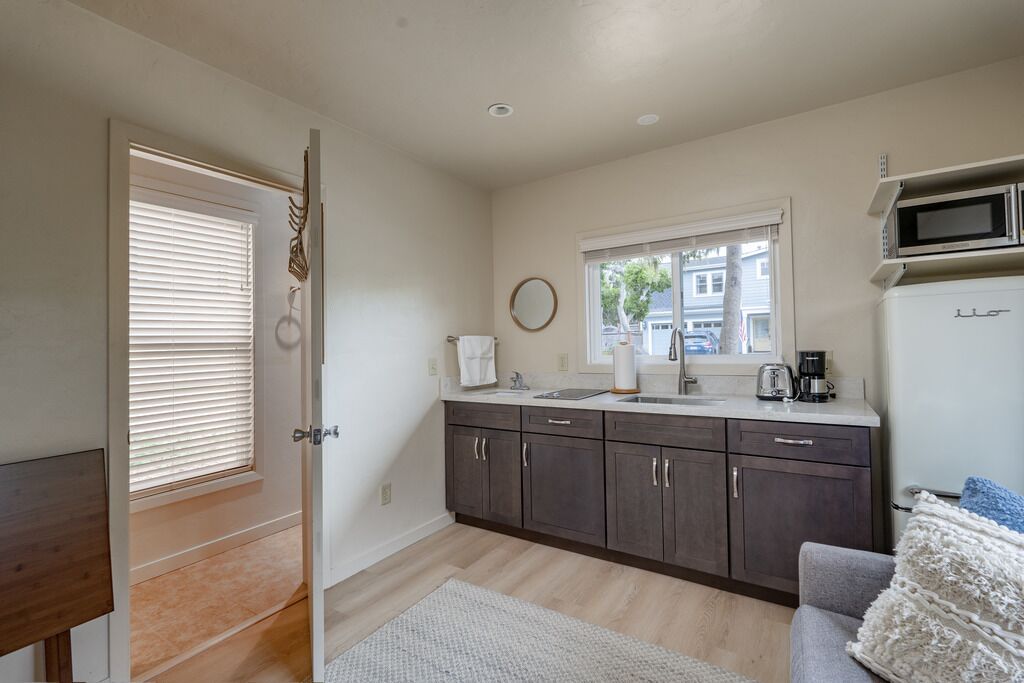A modern kitchen with dark cabinets, a white countertop, and a microwave.