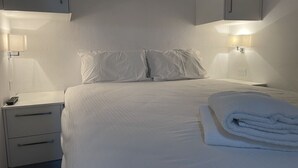 A hotel room with a neatly made bed, two bedside tables with lamps, and a folded towel on the bed. - Adorable 2 Bedroom Ski Chalet (Hotham Heights)