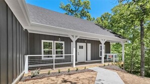 A modern two-story house with a covered porch, a small garden, and a pathway leading to the entrance. - The Rendezvous, 3BR/3BA Retreat on the Trail in Bella Vista (Bella Vista)