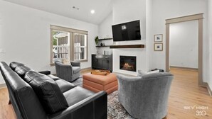 A modern living room with a fireplace, a flat-screen TV, and a grey sofa. - The Rendezvous, 3BR/3BA Retreat on the Trail in Bella Vista (Bella Vista)