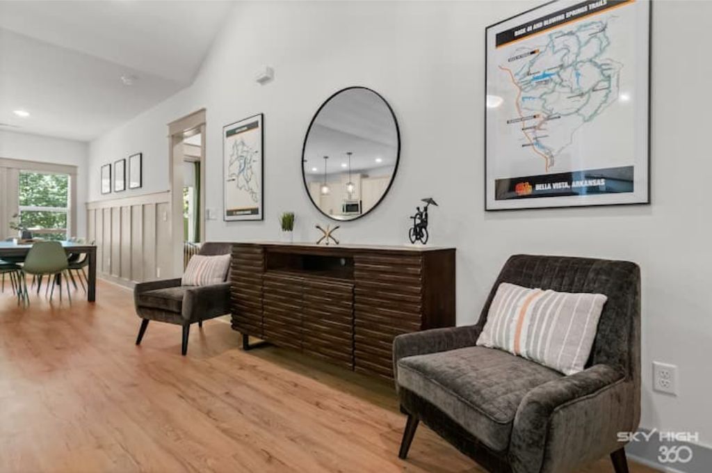 Uma sala de estar moderna com piso de madeira, um sofá escuro, um console de madeira e um grande mapa emoldurado na parede.