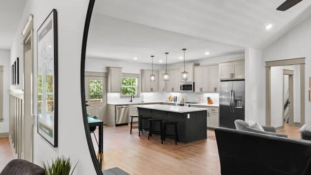 A modern kitchen with a central island, pendant lighting, and a view of the living area. - The Rendezvous, 3BR/3BA Retreat on the Trail in Bella Vista (Bella Vista)
