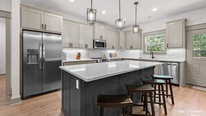 A modern kitchen with a large island, stainless steel appliances, and pendant lighting. - The Rendezvous, 3BR/3BA Retreat on the Trail in Bella Vista (Bella Vista)