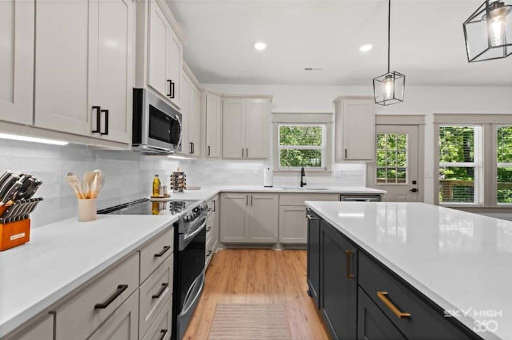 A modern kitchen with white cabinets, a central island, and a microwave.