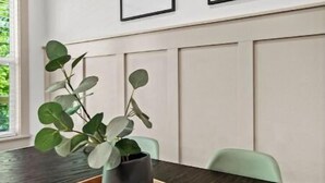 A modern dining area with a wooden table, a dark vase with green leaves, and two framed pictures on the wall. - The Rendezvous, 3BR/3BA Retreat on the Trail in Bella Vista (Bella Vista)